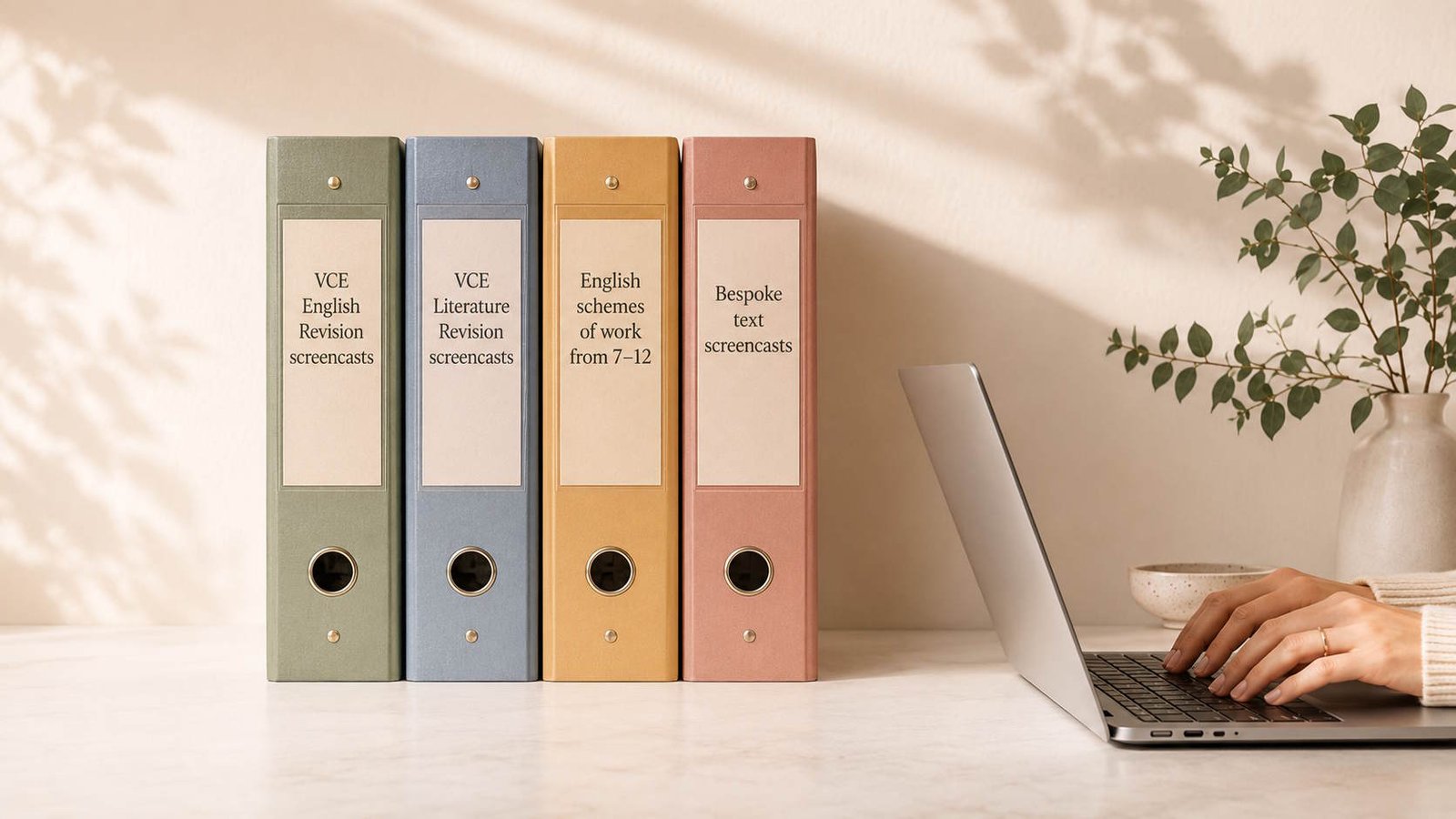 Four labelled resource folders beside a modern laptop in a warm workspace